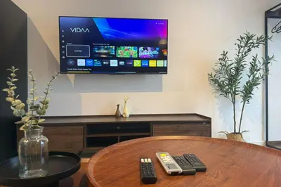a tv on a wall with two remote controls on a table at Majestic Residence KLCC by Luxe in Gua Sai