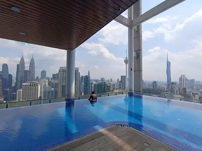 a woman sitting in a swimming pool on the top of a building at The Wisma Infinitum KLCC By Kuala Lumpur City in Kuala Lumpur