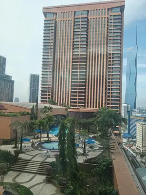 a view of a tall building with a pool and palm trees at Town suites Times Square in Kuala Lumpur