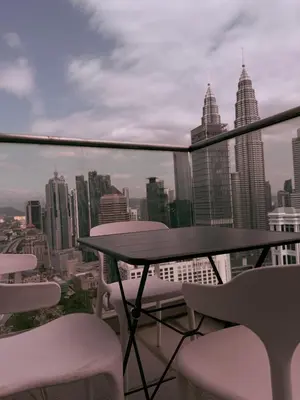 a table and chairs on a balcony with a view of a city at Poshpack Skyline Hostel in Kuala Lumpur