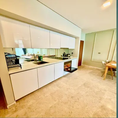 a kitchen with white cabinets and a table at Sky suites klcc by sky view in Kuala Lumpur