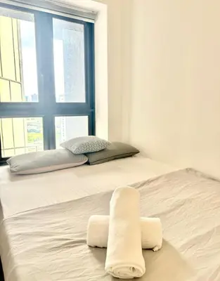 a bed with two towels on it in a room with a window at The Agile Residence By Signature in Kuala Lumpur