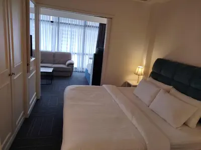 a bedroom with a large bed and a living room at Time Square Mountain View Apartment KL in Kuala Lumpur