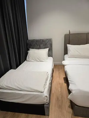 two beds in a room with black curtains at Kuala Lumpur Suites Quill in Kuala Lumpur