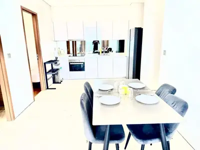 a white table with chairs and a white kitchen at Sky suites klcc by Aisyah in Kuala Lumpur