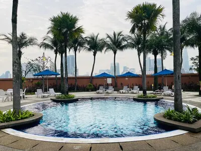 a large swimming pool with palm trees and chairs at Aurora Suites BUKIT At Times Square in Kuala Lumpur