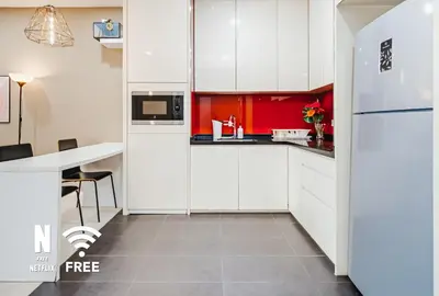 a kitchen with white cabinets and red accents at Arcoris SOHO Mont Kiara , Stylish 1 Bedroom Retreat in Kuala Lumpur
