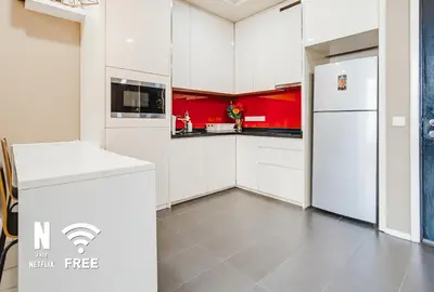 a kitchen with white cabinets and red walls at Arcoris SOHO Mont Kiara , Stylish 1 Bedroom Retreat in Kuala Lumpur