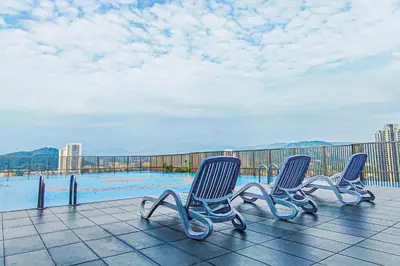 a group of three chairs sitting on a patio with a pool at Sky Pool at 3 Towers Ampang by HCK in Kuala Lumpur