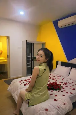 a young girl sitting on a bed with roses at 10 Mins to KLCC Cozy Place to Stay in Kuala Lumpur