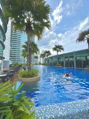 a person swimming in a large pool with palm trees at Apartment Kuala Lumpur City 3 Minutes To KLCC in Kuala Lumpur