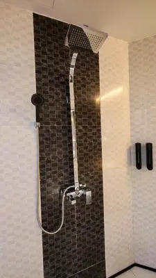 a shower in a bathroom with a tiled wall at pertama residency jacuzzi projector 120