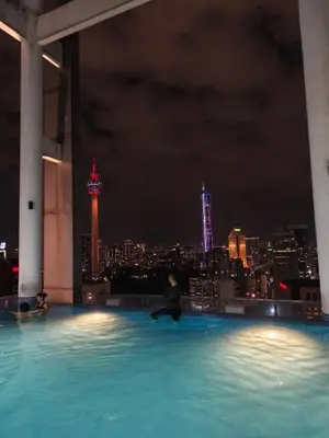 a person sitting in a pool with a city skyline at Luxe Colony By Urban Haven in Kuala Lumpur