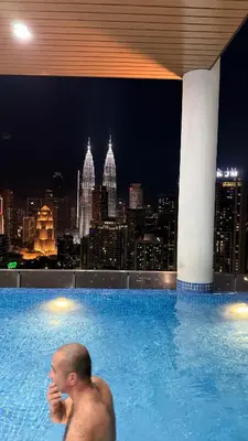 a man in a swimming pool with a view of a city at Colony Luxe By Swift Homes in Kuala Lumpur