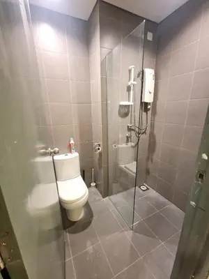 a bathroom with a toilet and a glass shower stall at Summer suites klcc by Amna in Kuala Lumpur