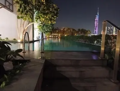 a view of the pool at night with the burj khalifa at B&B at TRION KL in Kuala Lumpur