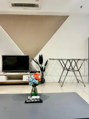 a living room with a tv and flowers in a vase at Chambers Suites By Grands in Kuala Lumpur