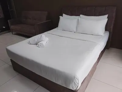 a bedroom with a bed with a chair and a white bedspread at Quill Luxury Suites KLCC in Kuala Lumpur