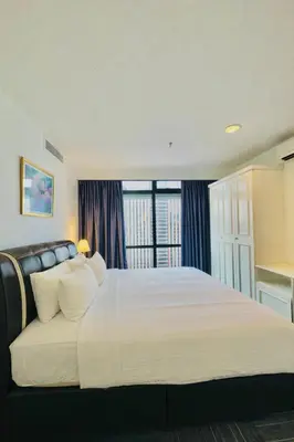 a bedroom with a large white bed and a window at Times Square Service Apartment KL in Kuala Lumpur