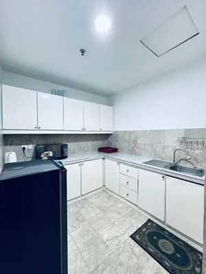 a kitchen with white cabinets and a black refrigerator at Times Square Service Apartment KL in Kuala Lumpur