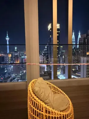 a wicker chair in front of a window with a view at Axon KL Infinity Pool Suites near Pavilion in Kuala Lumpur
