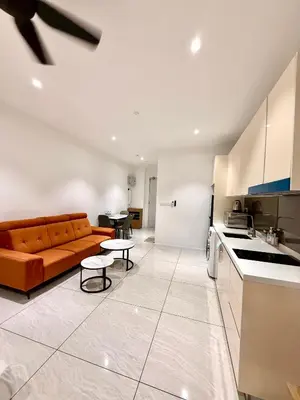 a living room with an orange couch and a kitchen at Kuala Lumpur Quill Residences By AR Stay in Kuala Lumpur