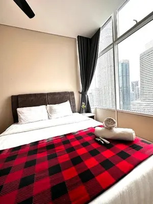 a bedroom with a bed with a red and black checkered blanket at SKY SUiTES KLCC BY RT GROUP in Kuala Lumpur