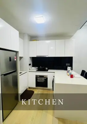 a kitchen with white cabinets and a refrigerator at Metro Star KLCC Living in Kuala Lumpur