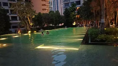a swimming pool with people in the water at night at Elite Suites at Agile Bukit Bintang Kuala Lumpur in Kuala Lumpur