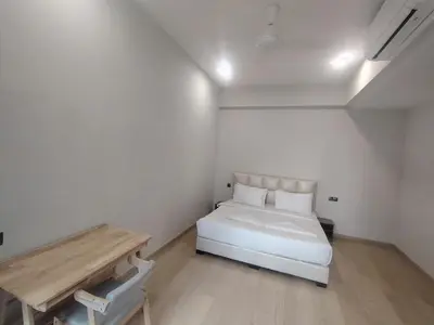 a white bedroom with a bed and a wooden table at KL Suites At Star KLCC in Kuala Lumpur