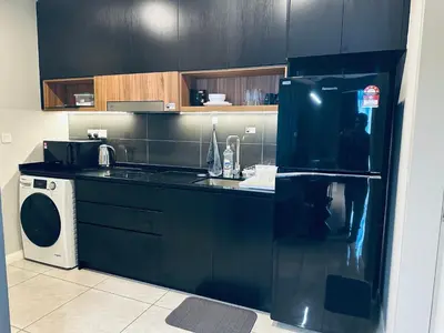 a black kitchen with a refrigerator and a washing machine at Luxury Residence At Axon in Kuala Lumpur