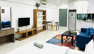a living room with a blue couch and a kitchen at LuxeHive Stay in Kuala Lumpur