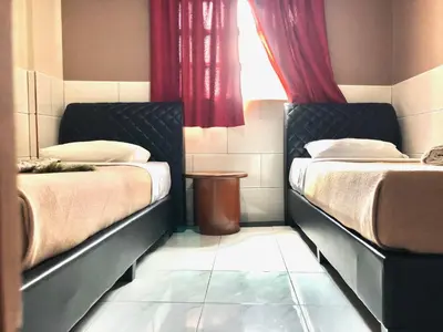 a bedroom with two beds and a window with red curtains at Adamson Park Kuala Lumpur in Kuala Lumpur