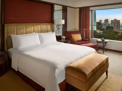 a hotel room with a bed and a chair and a window at Shangri-La Kuala Lumpur in Kuala Lumpur