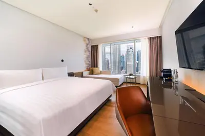a bedroom with a large white bed and a couch at Traders Hotel, Kuala Lumpur in Kuala Lumpur