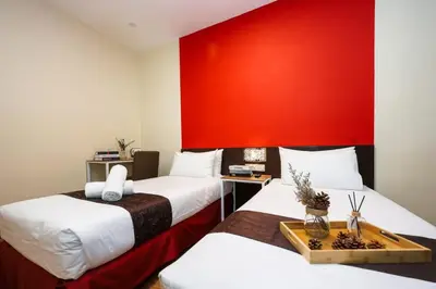 two beds in a room with a red wall at MyCiti Hotel Kuala Lumpur - formerly known as Citin Hotel Masjid Jamek in Kuala Lumpur