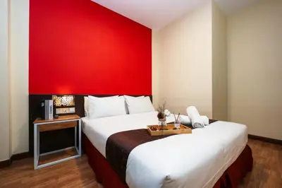 a hotel room with a red wall and two beds at MyCiti Hotel Kuala Lumpur - formerly known as Citin Hotel Masjid Jamek in Kuala Lumpur
