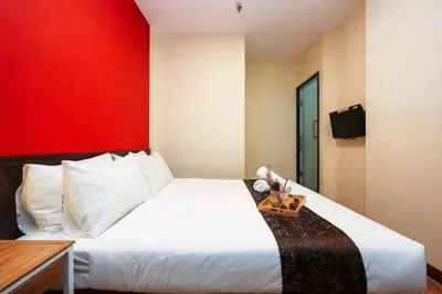 a bedroom with a white bed with a red wall at MyCiti Hotel Kuala Lumpur - formerly known as Citin Hotel Masjid Jamek in Kuala Lumpur