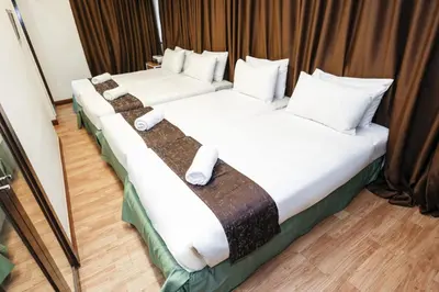 two beds in a hotel room with white pillows at MyCiti Hotel Kuala Lumpur - formerly known as Citin Hotel Masjid Jamek in Kuala Lumpur