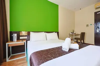 a hotel room with two beds and a green wall at MyCiti Hotel Kuala Lumpur - formerly known as Citin Hotel Masjid Jamek in Kuala Lumpur