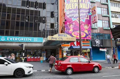 a red car parked on a street in a city at Tang City Hotel, Petaling Street, Merdeka PNB 118 Tower in Kuala Lumpur