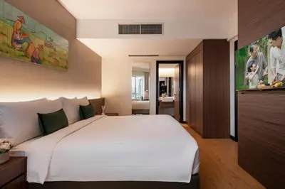 a bedroom with a large white bed and a bathroom at Oakwood Hotel & Residence Kuala Lumpur in Kuala Lumpur
