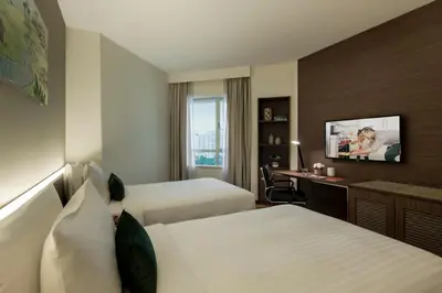 a hotel room with two beds and a desk at Oakwood Hotel & Residence Kuala Lumpur in Kuala Lumpur