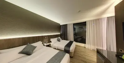 a hotel room with two beds and a window at Flora by Crossroads Hotel in Kuala Lumpur