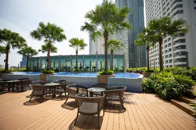 a patio with tables and chairs and palm trees at Vortex KLCC by Luxury Suites Asia in Kuala Lumpur