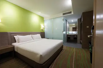 a bedroom with a large white bed and a bathroom at Cosmo Hotel Kuala Lumpur in Kuala Lumpur