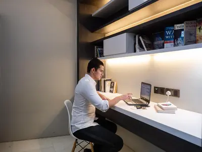 a man sitting at a desk with a laptop computer at The Penthouse KLCC in Kuala Lumpur