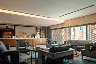 a living room with chairs and a table at Hotel Stripes Kuala Lumpur, Autograph Collection in Kuala Lumpur