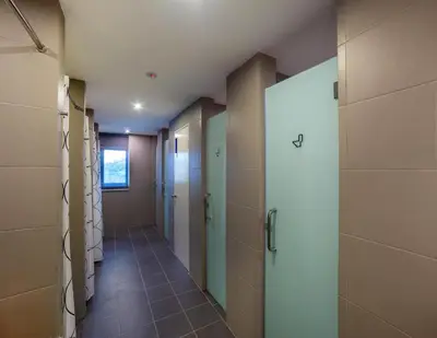 a corridor of a bathroom with doors and tile floors at Riccarton Capsule Hotel in Kuala Lumpur