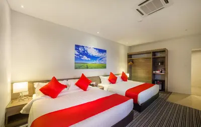 two beds in a hotel room with red pillows at Riccarton Capsule Hotel in Kuala Lumpur